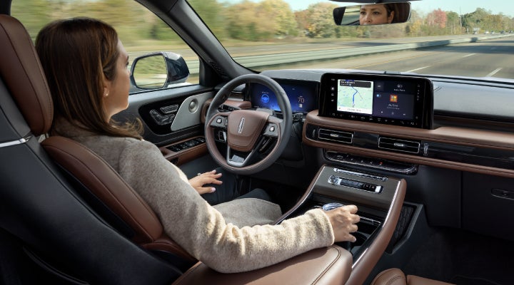 A 2026 Lincoln Aviator® SUV is being driven hands-free on a highway near a forest | Crest Lincoln in Sterling Heights MI