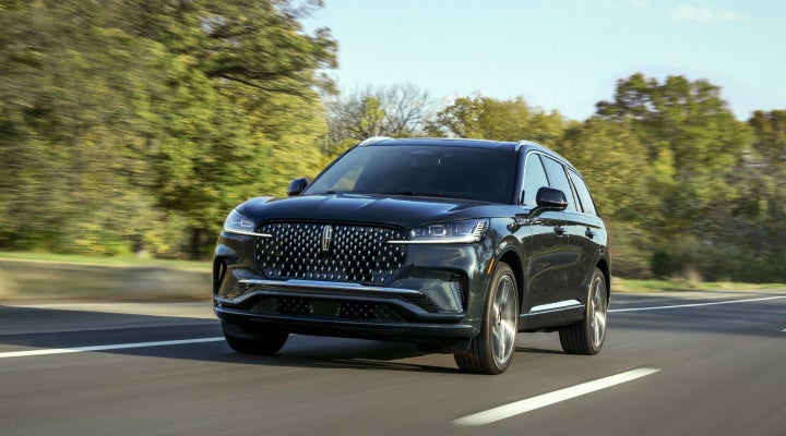 A 2026 Lincoln Black Label™ Aviator® SUV is being driven down a road lined with trees. | Crest Lincoln in Sterling Heights MI