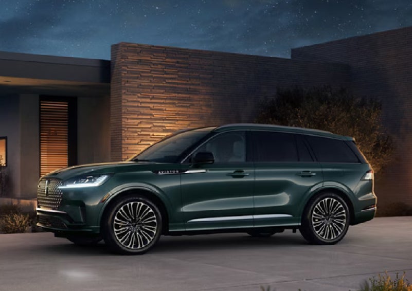 A green 2027 Lincoln Aviator® SUV is parked outside a contemporary home. | Crest Lincoln in Sterling Heights MI