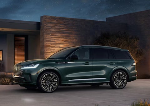 A green 2027 Lincoln Aviator® SUV is parked outside a contemporary home. | Crest Lincoln in Sterling Heights MI