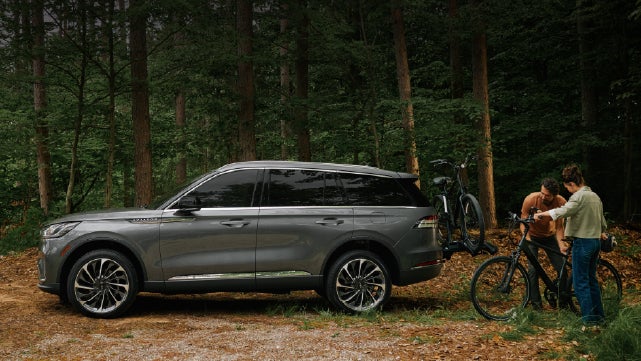 A father and son load e-bikes on a bike rack attached to a 2027 Lincoln Aviator® SUV. | Crest Lincoln in Sterling Heights MI