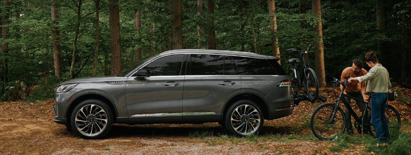 A father and son load e-bikes on a bike rack attached to a 2027 Lincoln Aviator® SUV. | Crest Lincoln in Sterling Heights MI