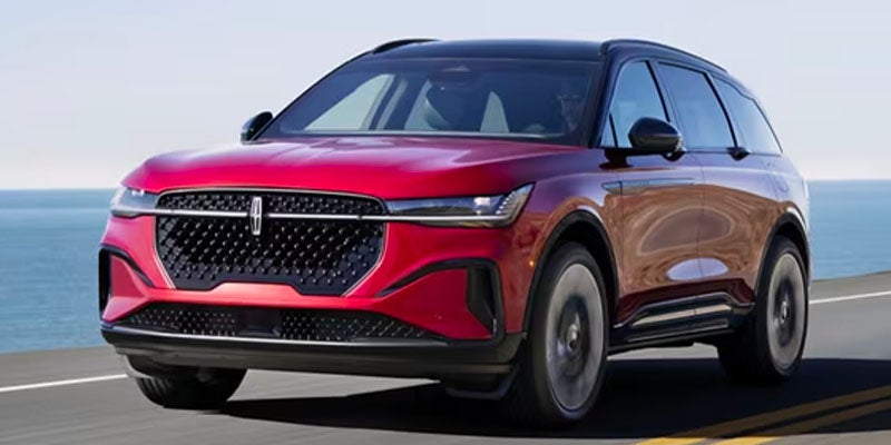 Red Lincoln SUV driving on a coastal road