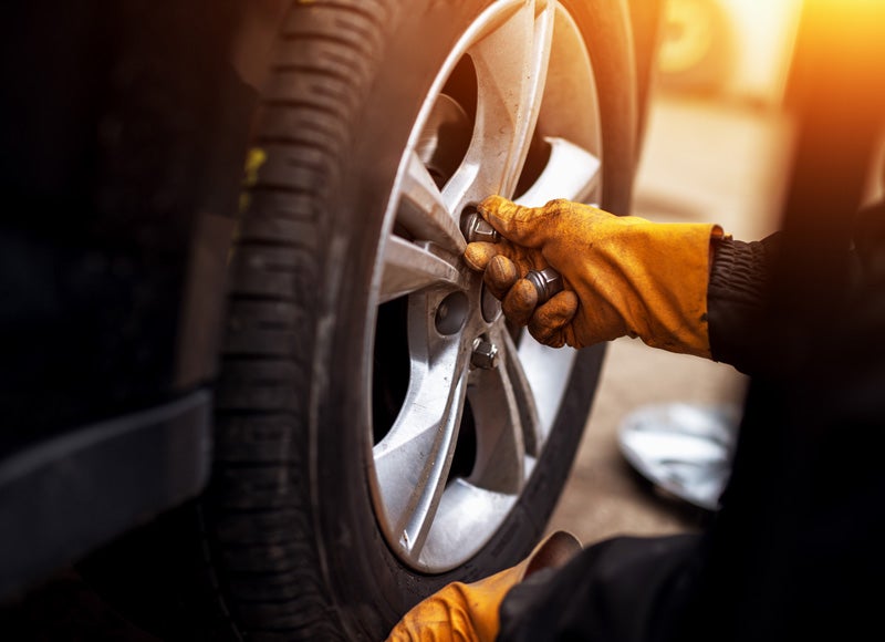 A technician is tightening lug nuts on a car wheel.